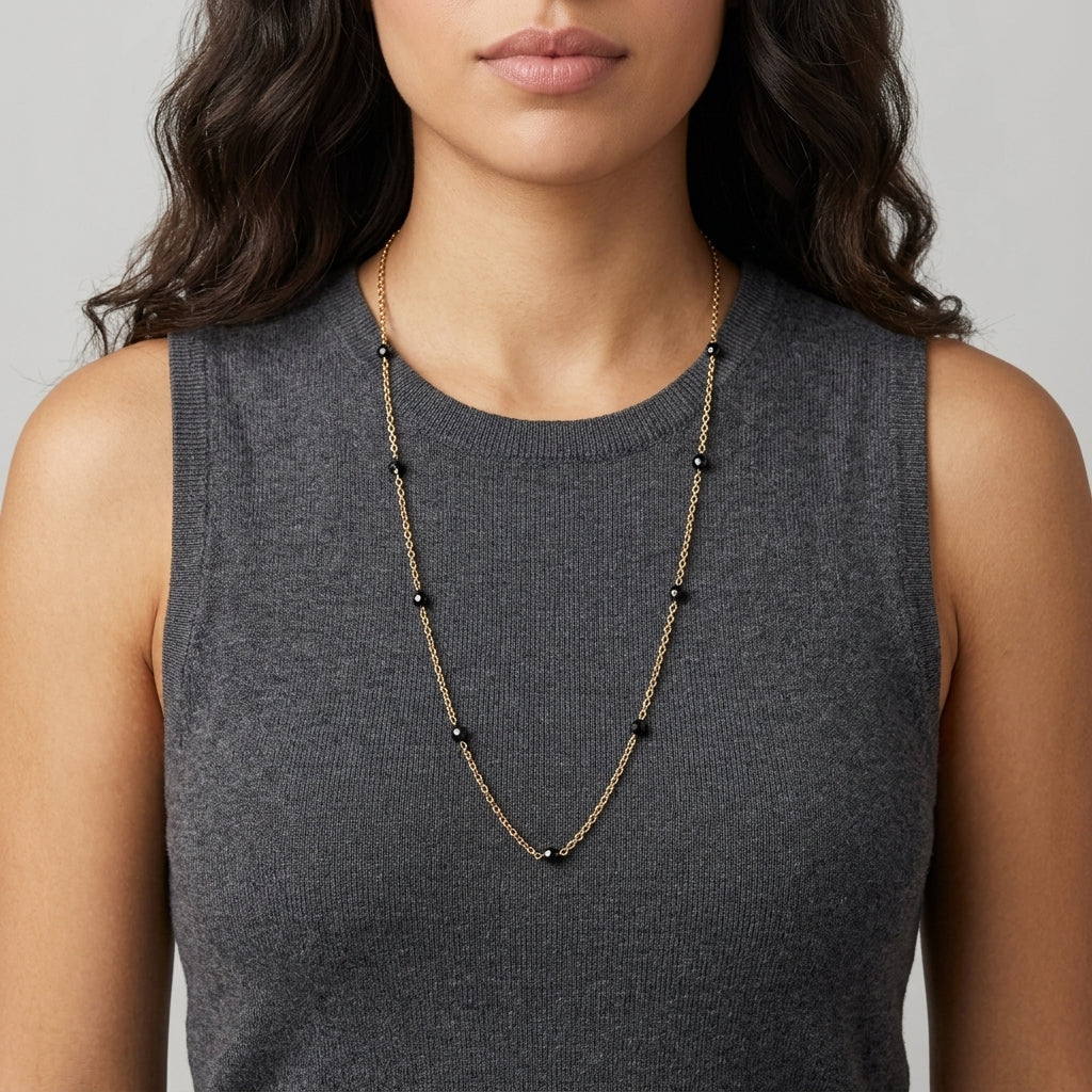 Woman in a dark sleeveless top with dark hair wearing a Minuit Black Glass Beaded Link Necklace