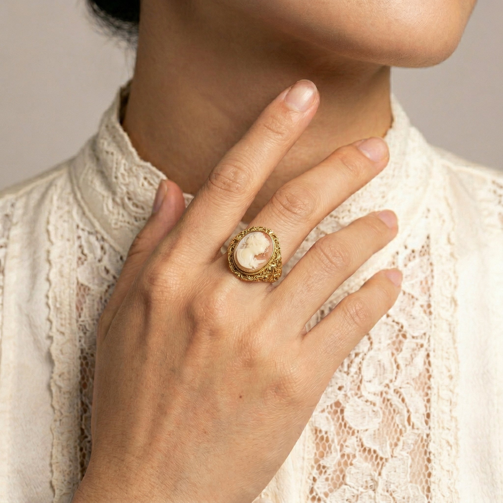 Close-up of a hand wearing a gold tone Twin Muse And Bird Cameo Ring