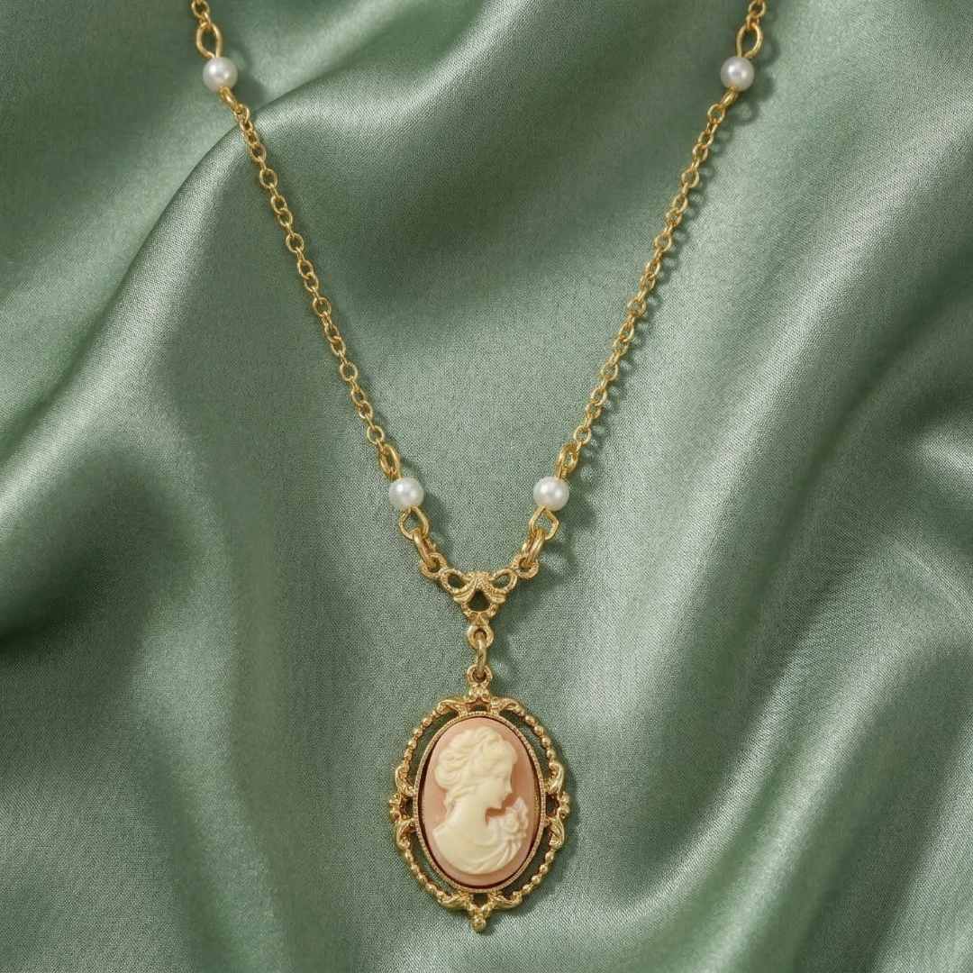 Gold faux pearl necklace with a cameo pendant on a green satin background