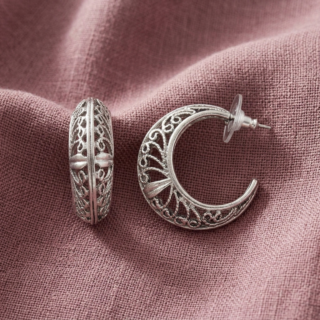 Silver Ornate Filigree Hoop Earrings displayed on a textured dusty rose fabric background.