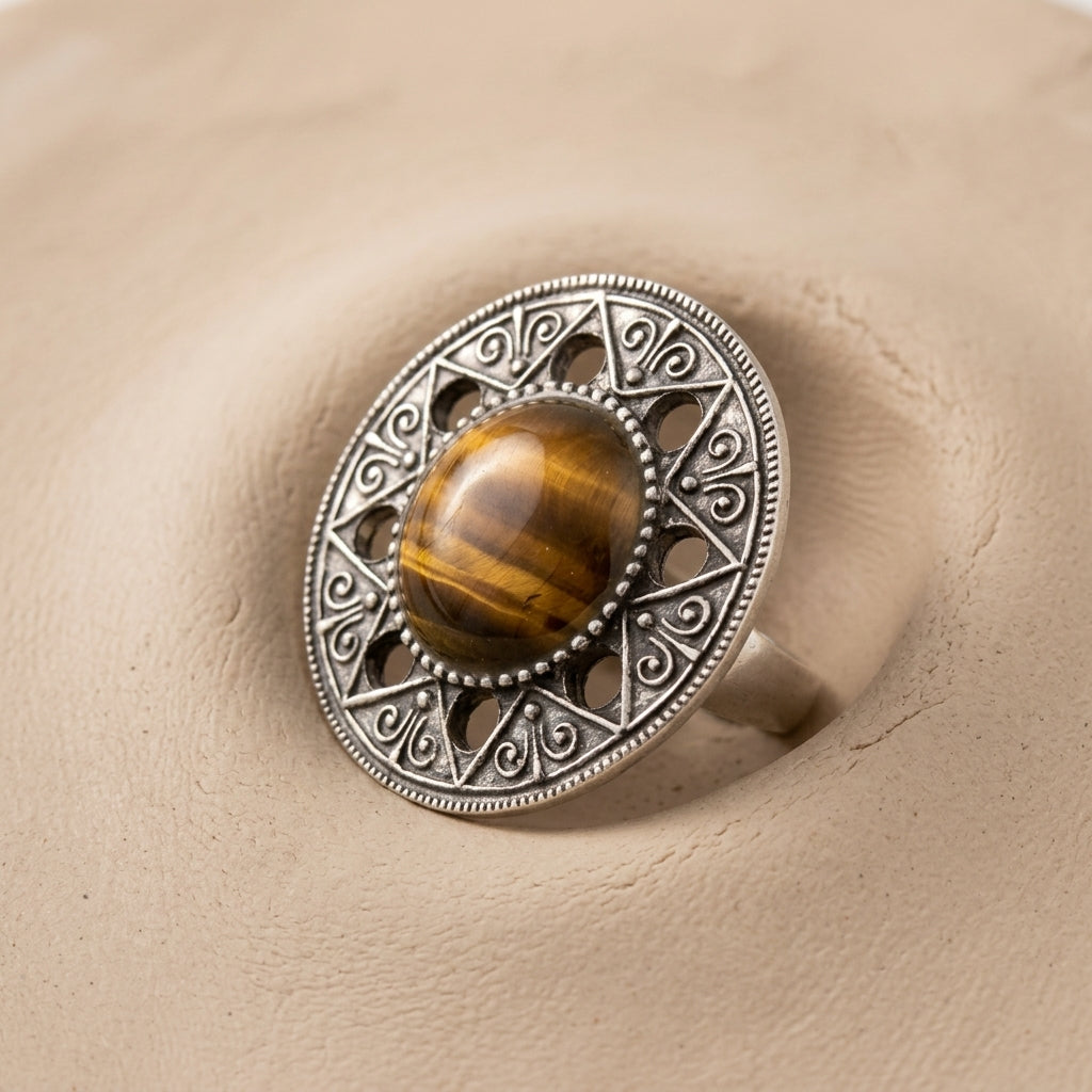 Aztec Mandala Gemstone Tigers Eye Ring displayed on a textured beige surface.