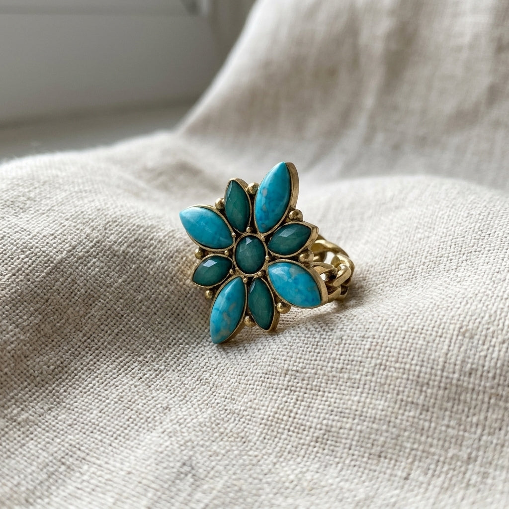 Gold ring with turquoise stones on a textured fabric surface