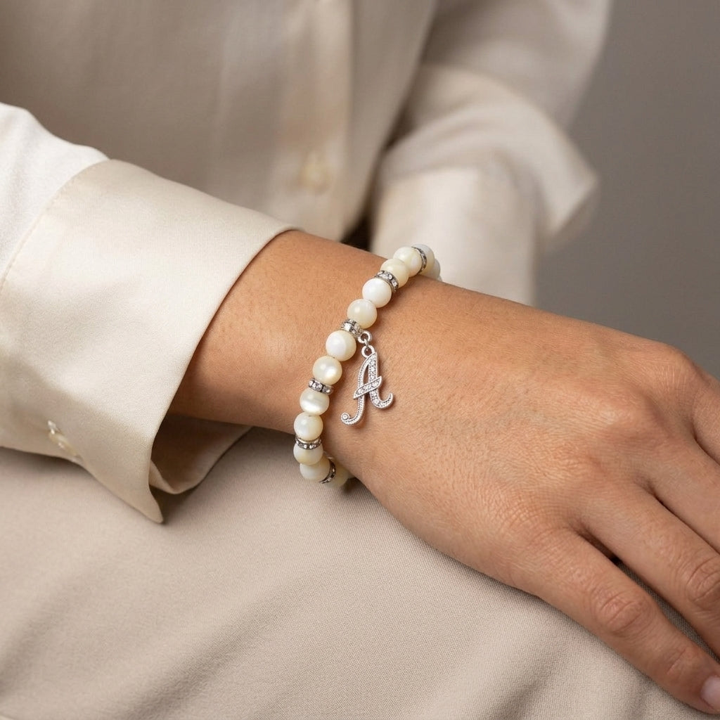 Mother Of Pearl Crystal Initial Charm Bracelet with a silver 'A' on a wrist against a neutral background
