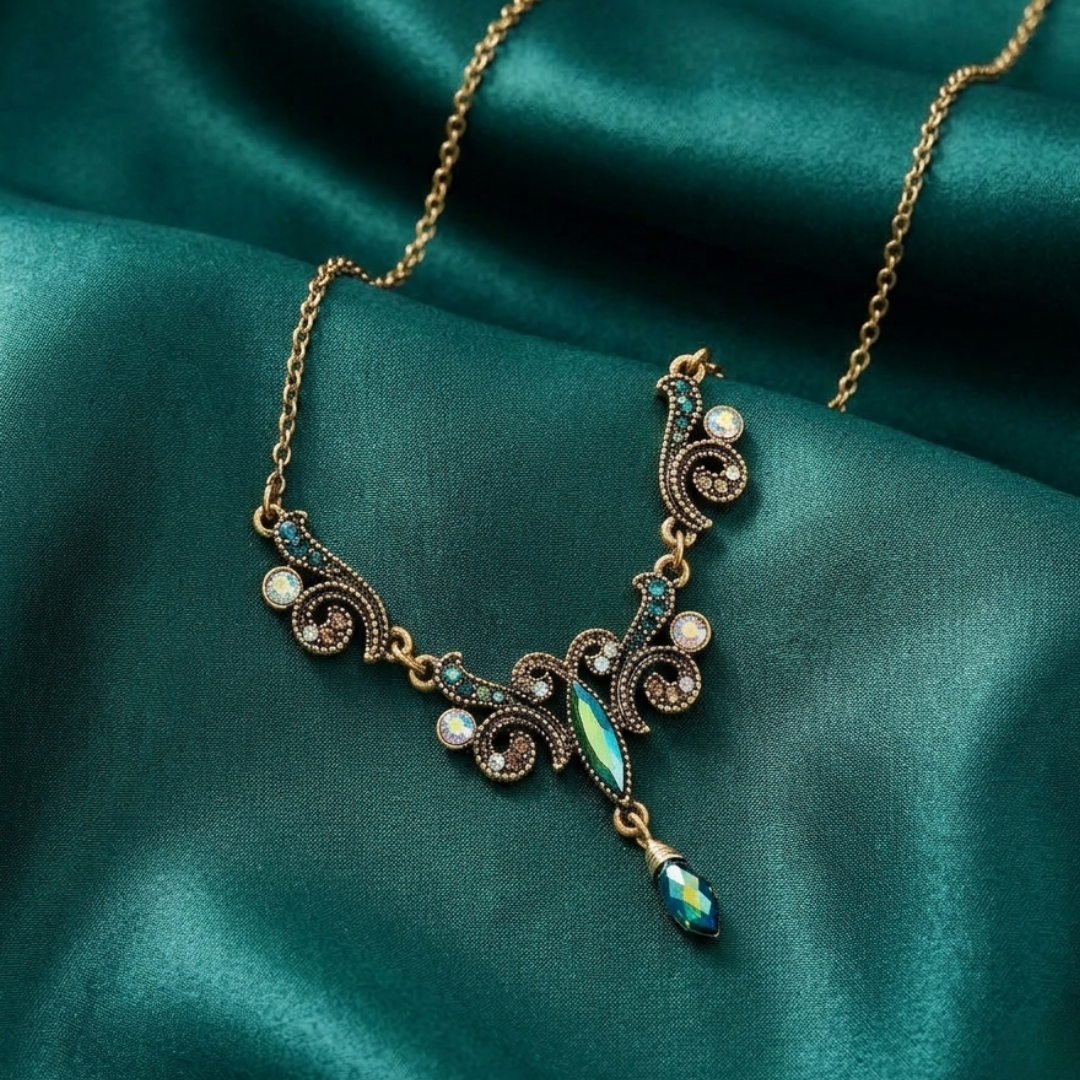 Decorative peacock plumage style necklace with AB crystals on a teal fabric background