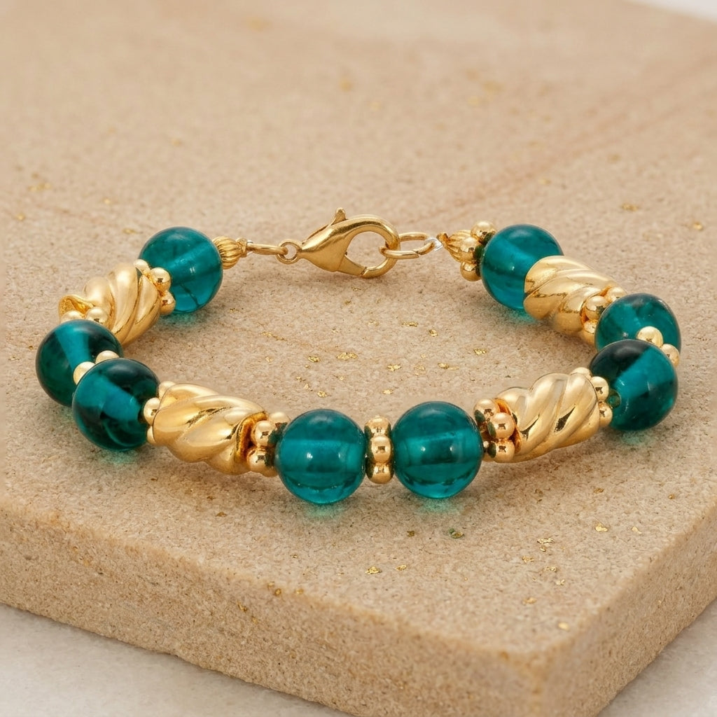 Teal Round Glass & Twisted Gold Tone Bead Bracelet on a beige stone surface