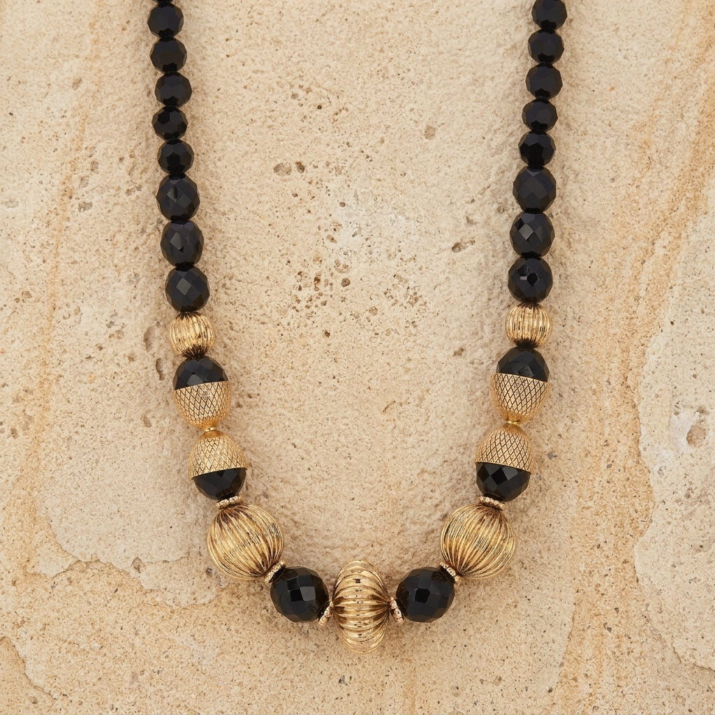 Black Fire Polished Strand Corrugated Bead Necklace on a beige stone surface