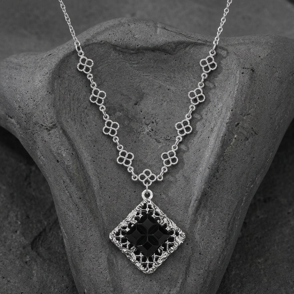 Belladonna Black Glass Stone Filigree Pendant Necklace resting on dark stone