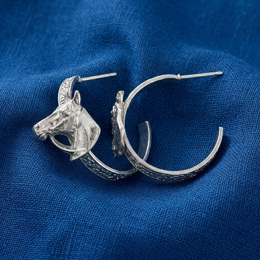 Pewter tone Etch Floral Horse Head Hoop Earrings displayed on a textured blue fabric background.