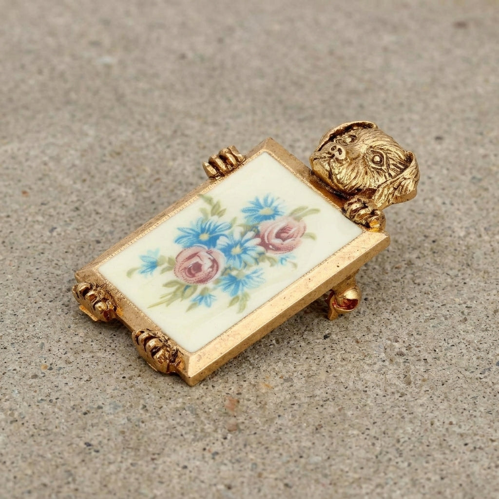 Decorative gold tone dog brooch with floral design and gold frame on a textured surface