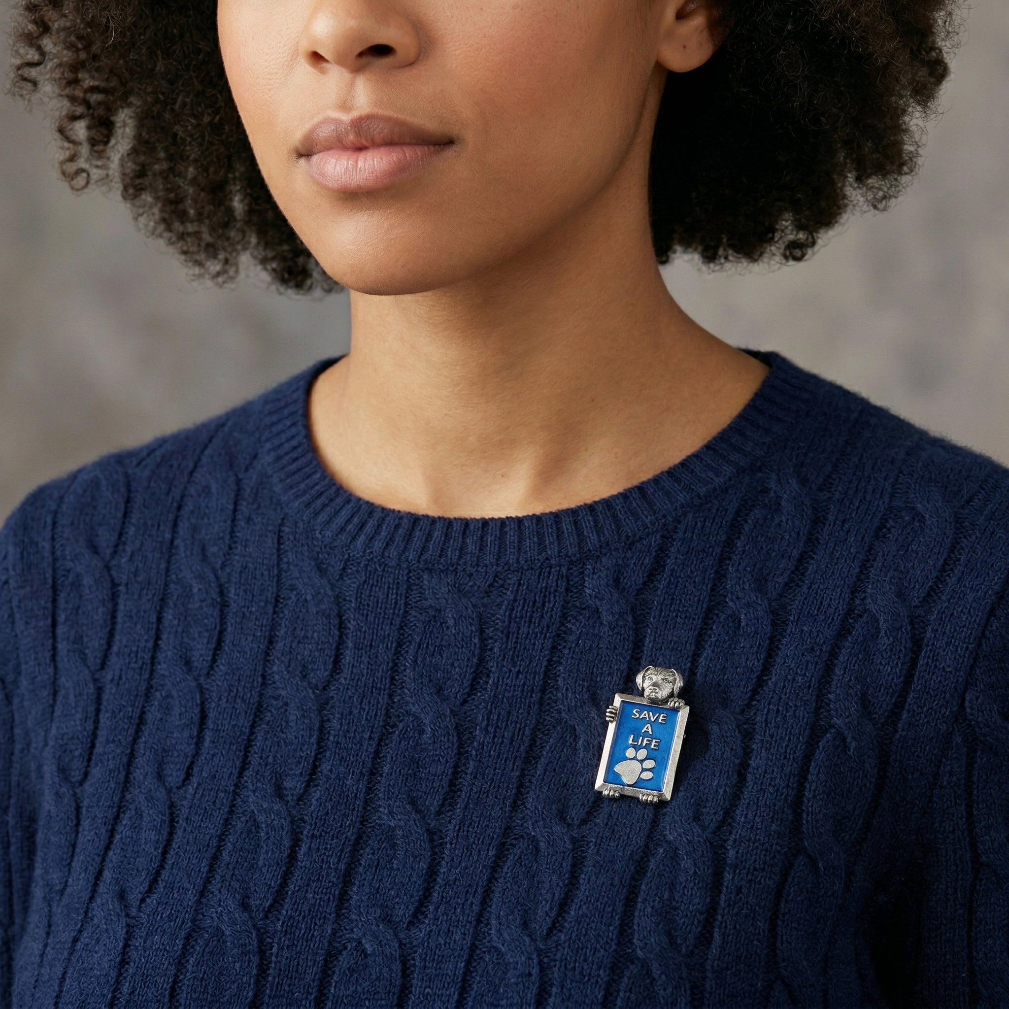 Woman in a blue sweater wearing our Pewter Dog Blue Enamel Save A Life Pin