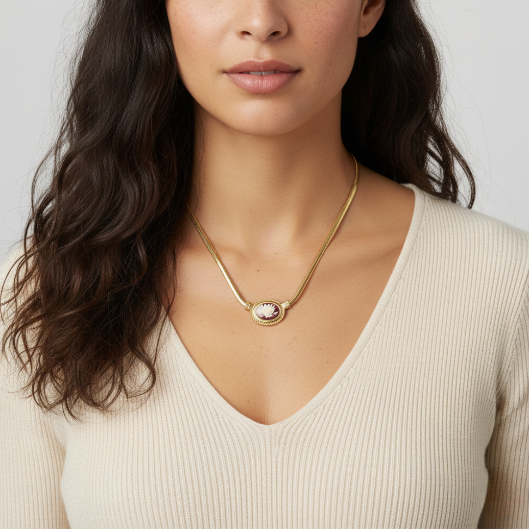 Woman wearing a gold necklace with a cameo pendant on a white background