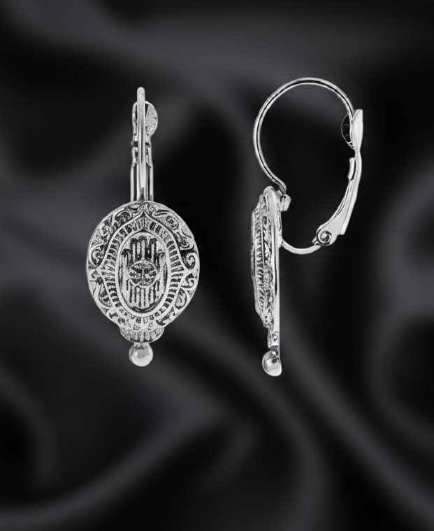 Silver earrings on a black satin background