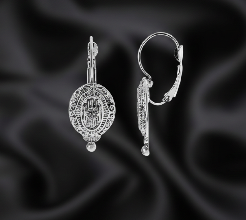 Silver earrings on a black satin background