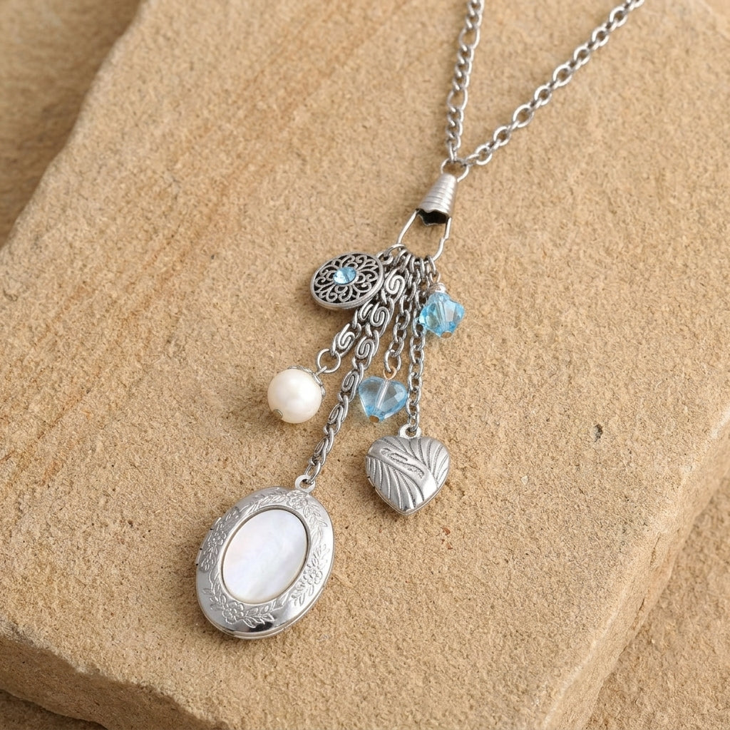 Aquamarine Crystal Mother Of Pearl Charms And Locket Necklace resting on sandstone surface