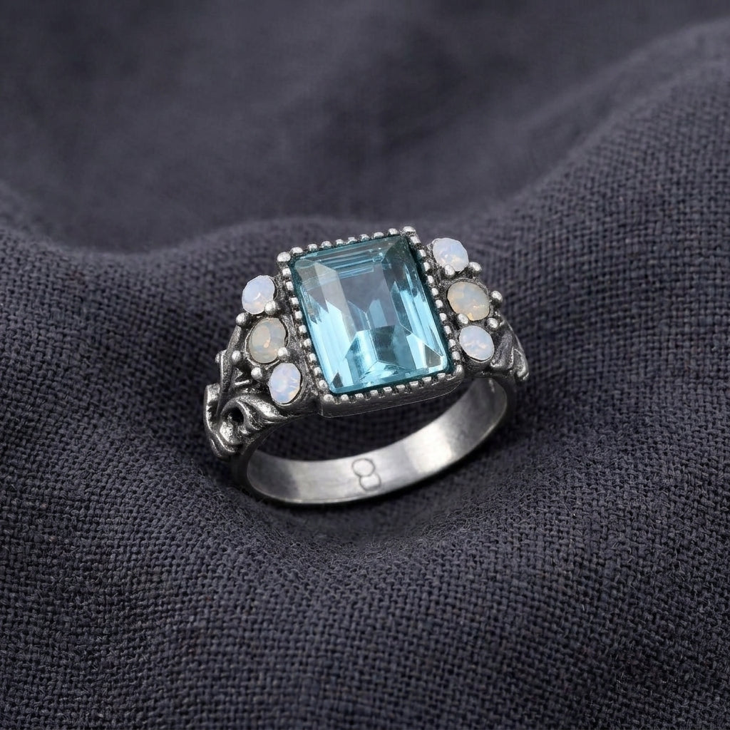 Aquamarine Crystal Rectangular Blue Crystal Opal Stone Ring resting on dark linen fabric