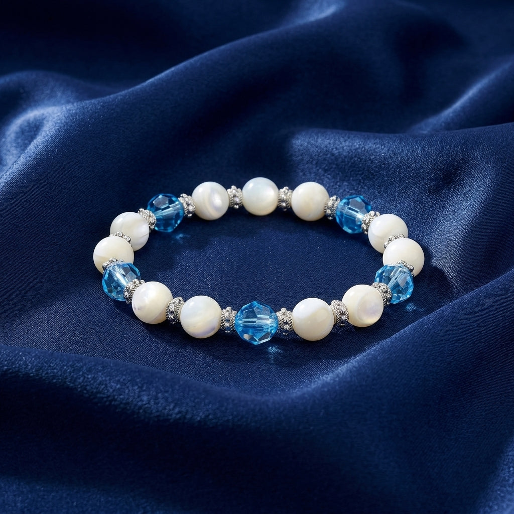 Aquamarine Crystal Mother Of Pearl Stretch Bracelet resting on dark blue satin fabric