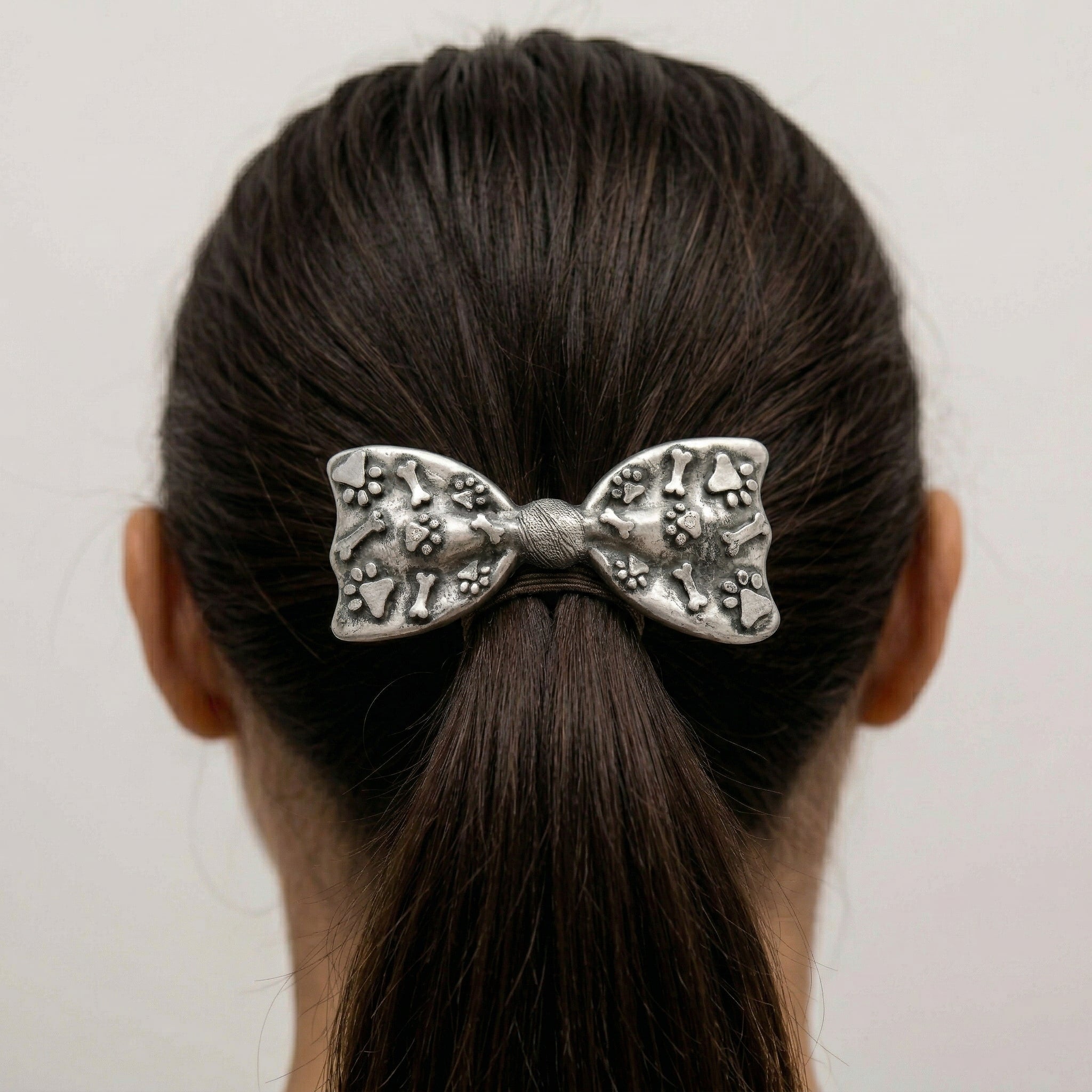 Woman with dark hair wearing our Antiqued Paws & Bones Bow Barrette Hair Clip
