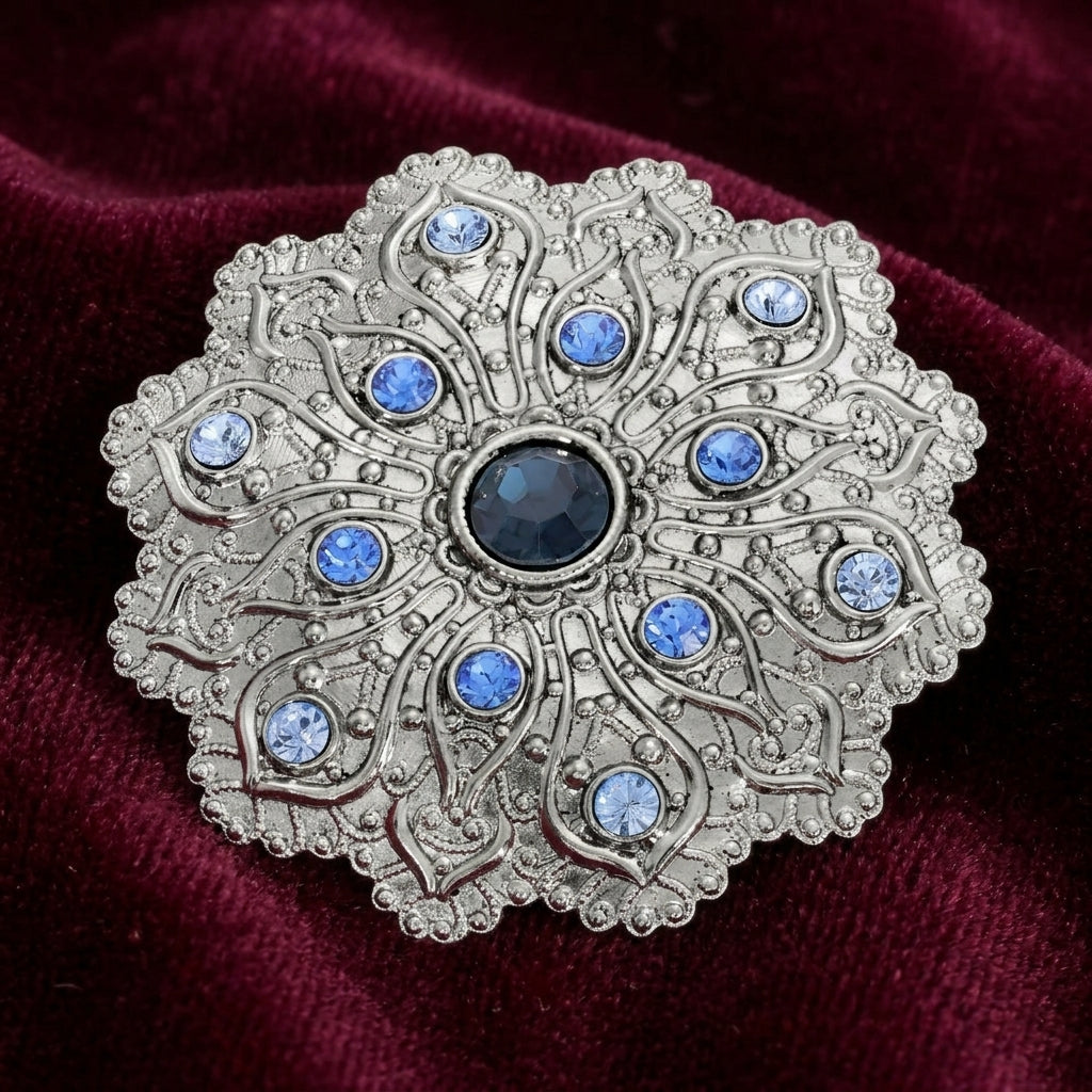 Imperial Silver Tone Flower Blue Crystal Brooch resting on dark red fabric