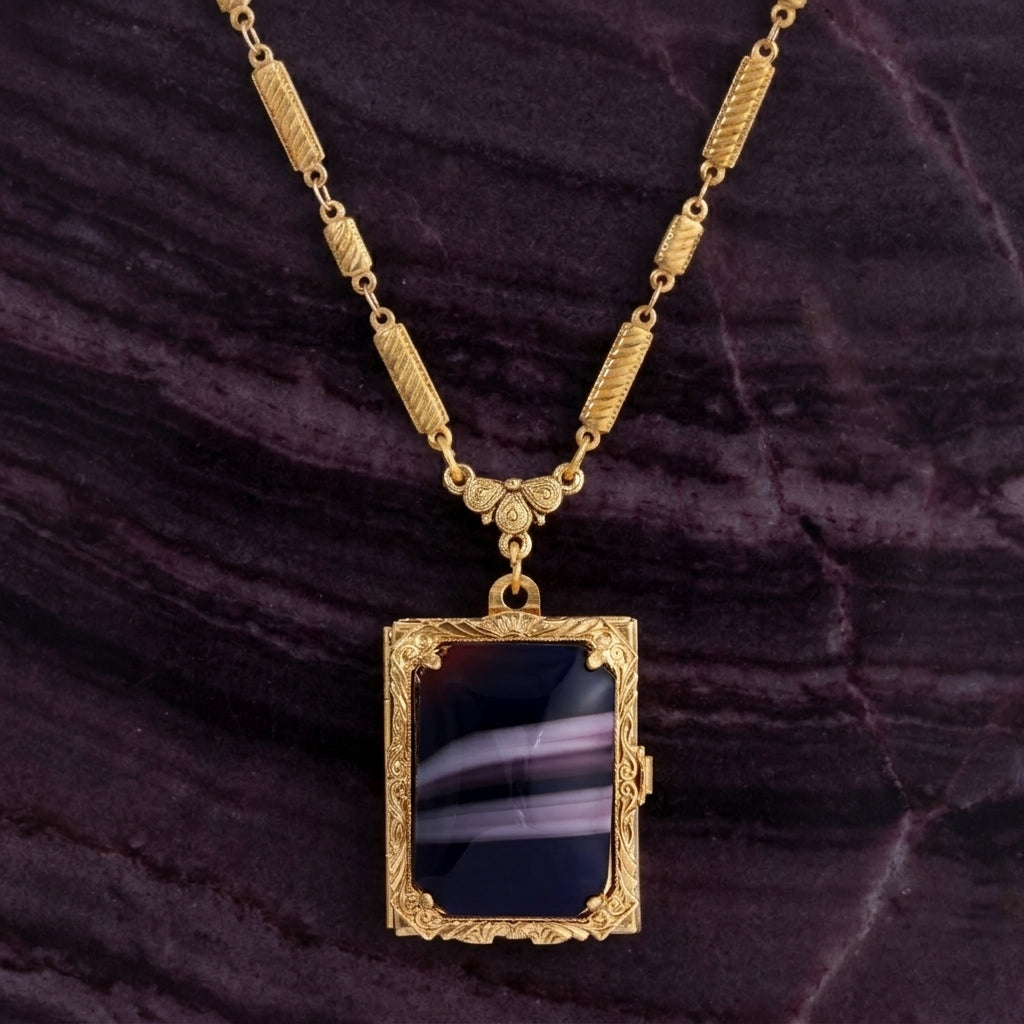 Purple stone Ol' Family Album Stone Locket Necklace resting on dark stone surface
