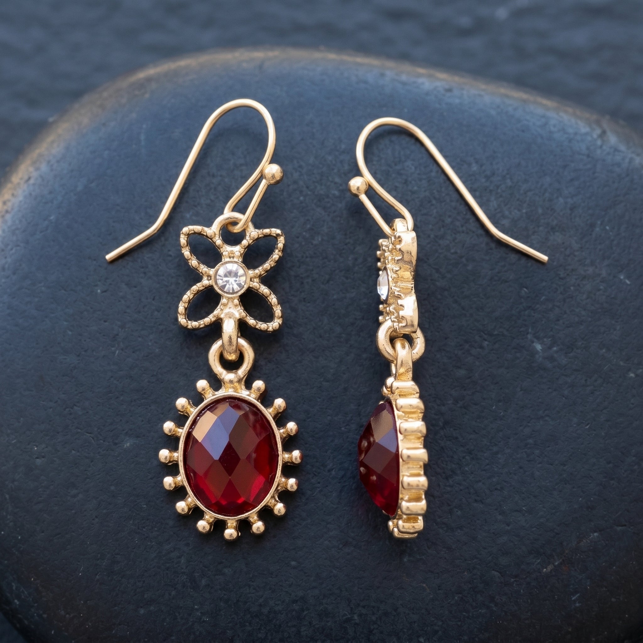 Red Sol Oval Stone Crystal Dangle Earrings on a dark surface