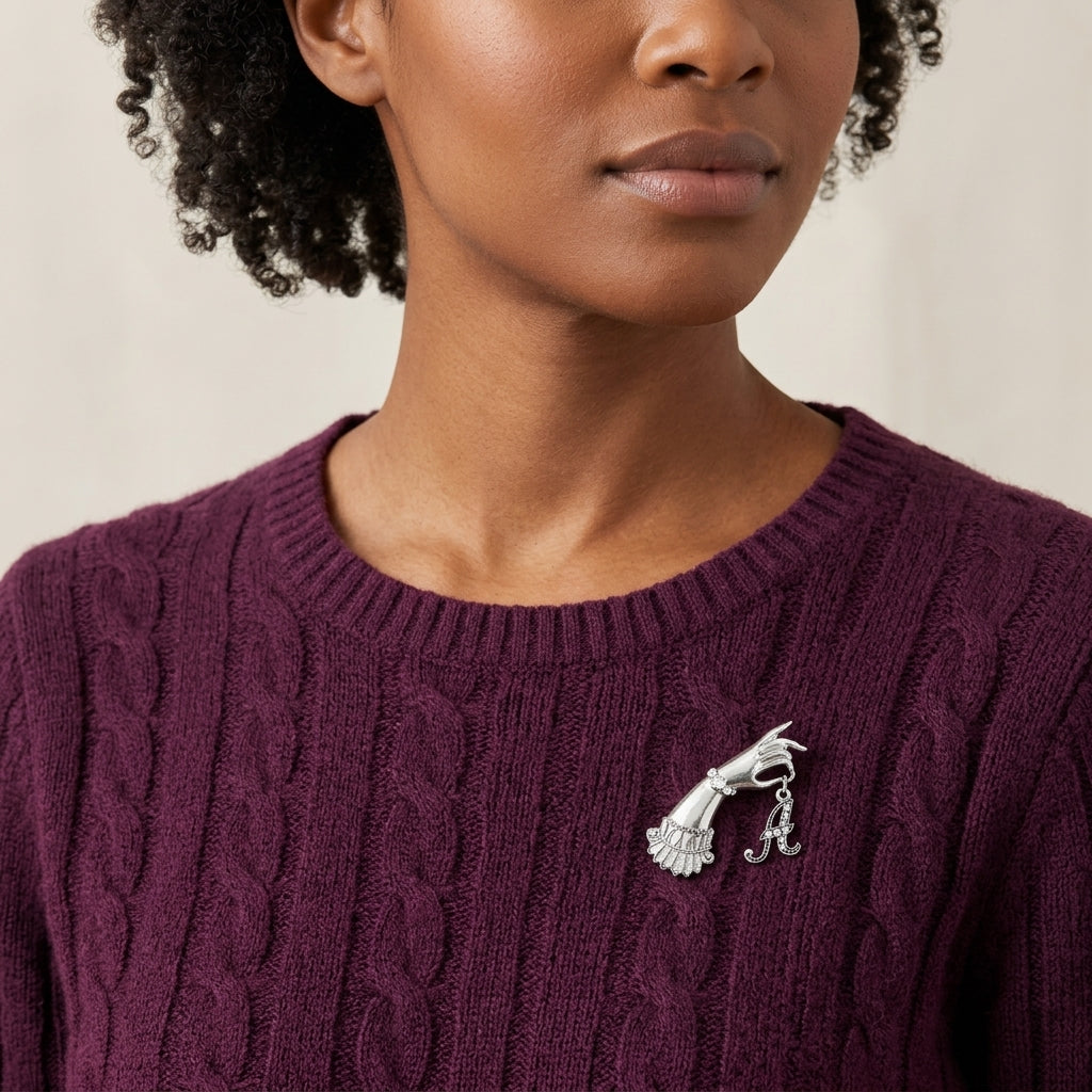 Woman in a maroon sweater wearing our Belle Epoch Victorian Hand Model Crystal Initial Pin