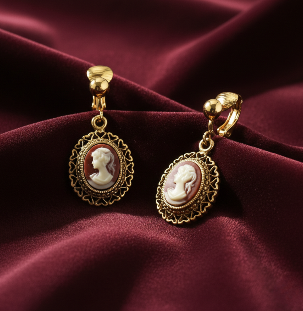 Gold earrings with cameo design on a burgundy fabric background