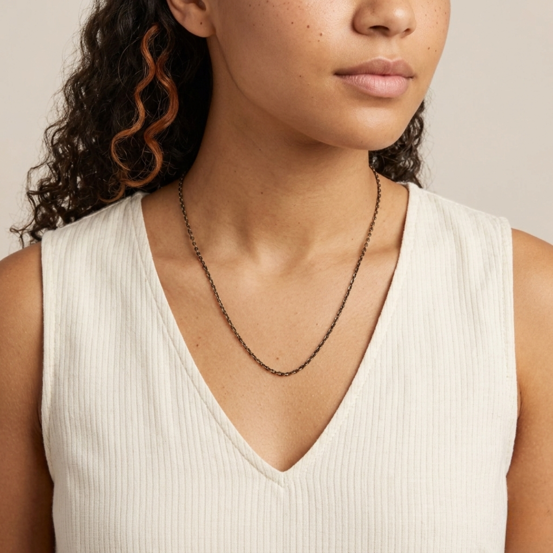 Woman wearing a dark chain necklace with a neutral background
