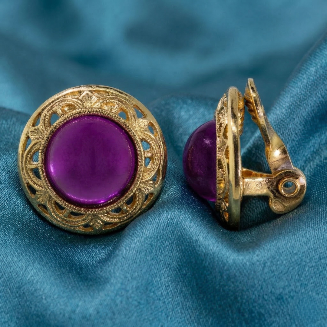 Gold earring with purple gemstone on a blue fabric background