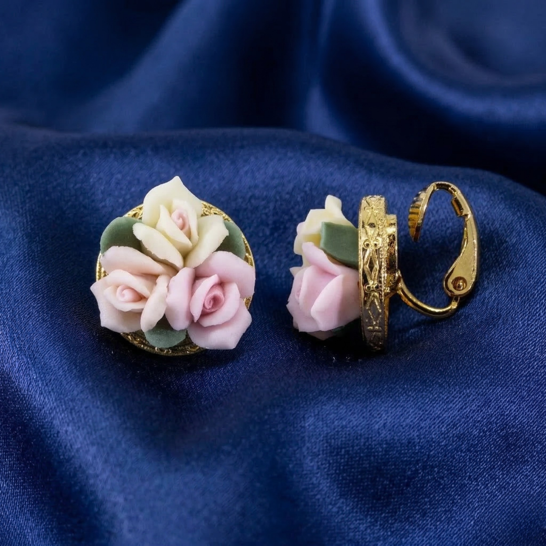 Floral porcelain rose earrings with gold accents on a blue fabric background