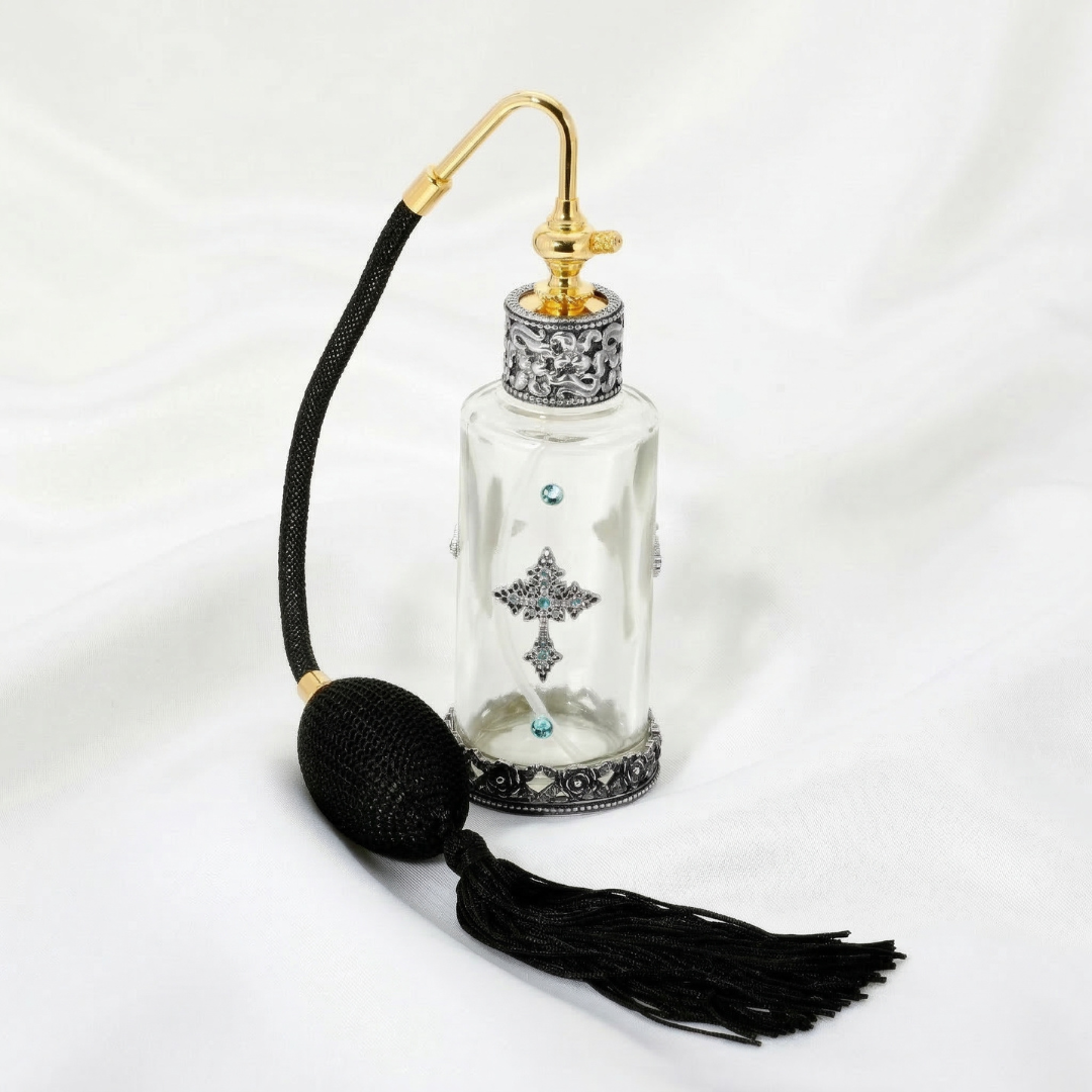 Decorative glass spray bottle with gold cap and black tassel on a white background