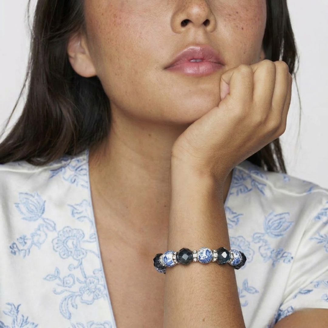 Woman wearing a bracelet with blue willow and light blue beads on a white background