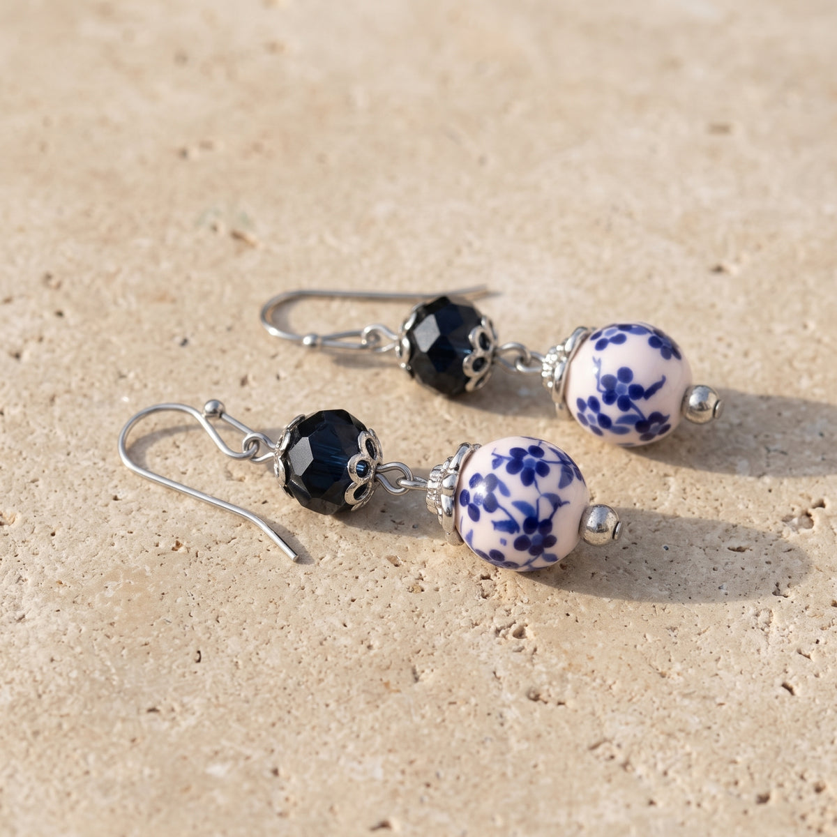 Blue Willow Dark Blue And Beaded Dangle Earrings resting on flat beige limestone
