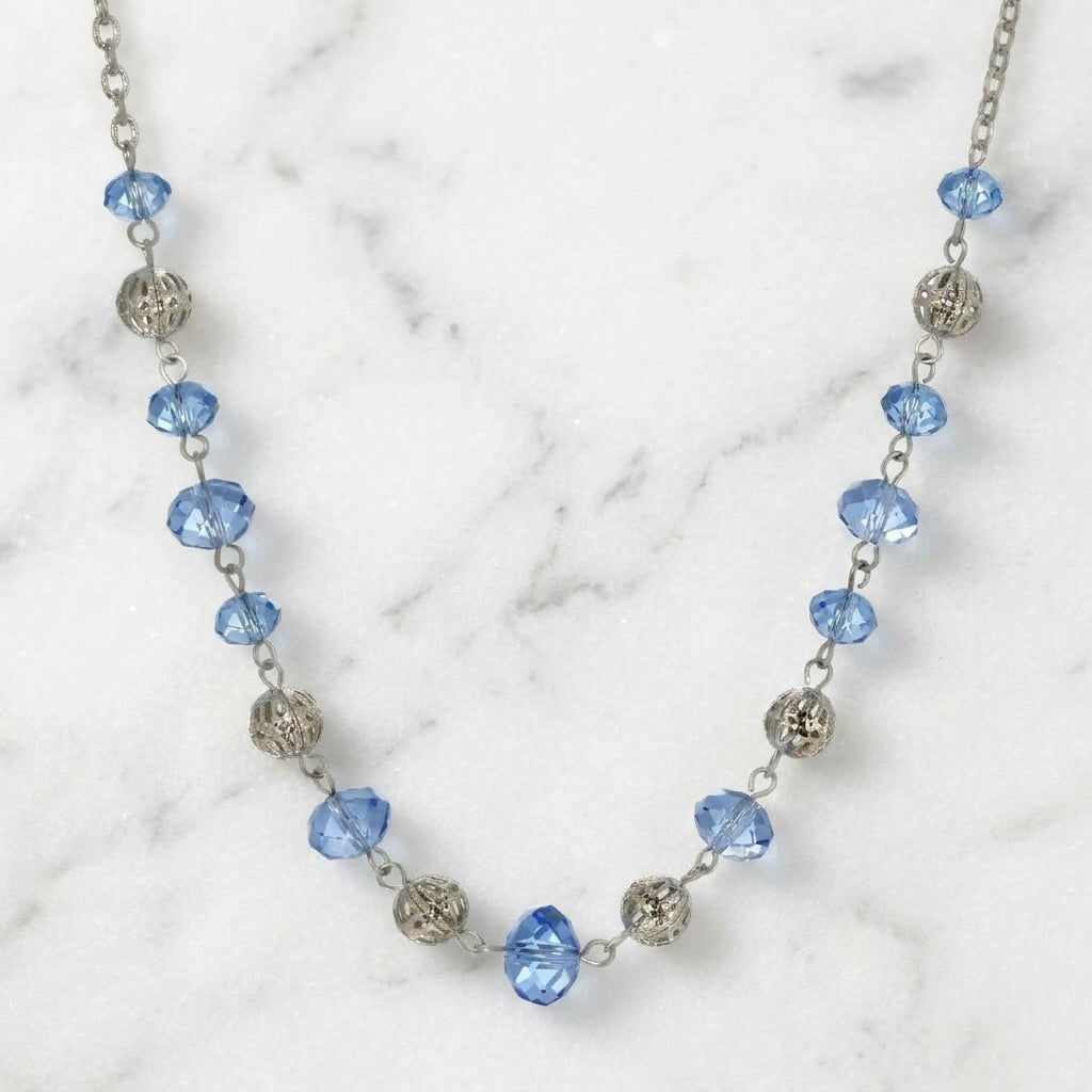 Filigree Puff Bead Blue Crystal Chain Necklace resting on marble surface