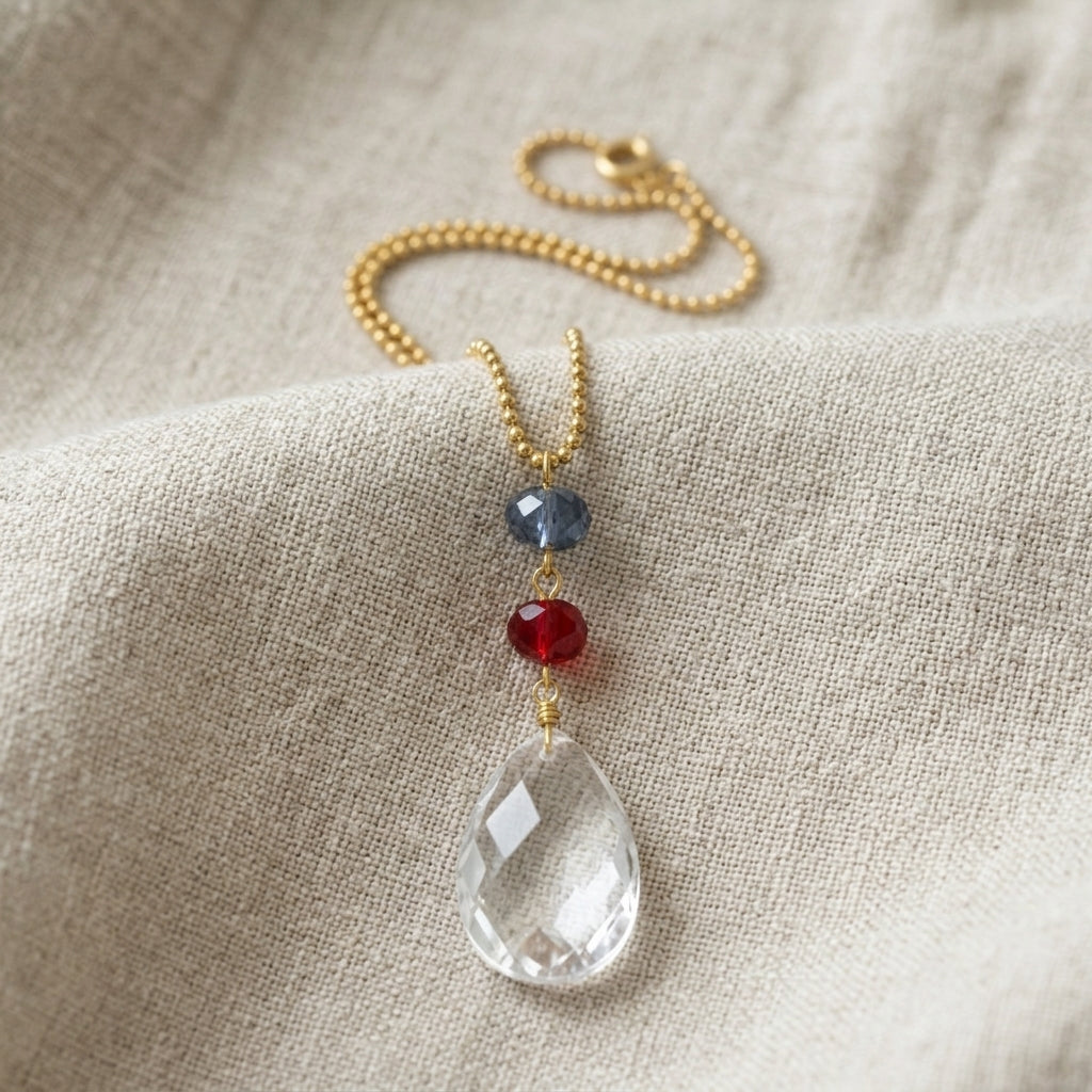 Necklace with a clear crystal pendant and colorful red and blue beads on a beige fabric background
