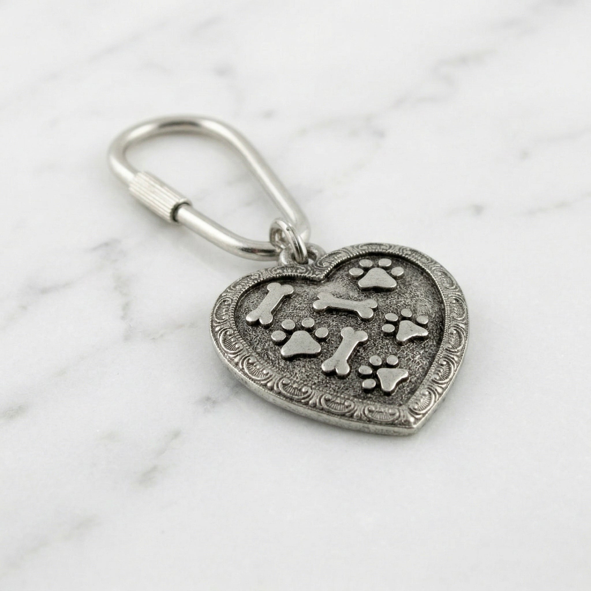 Bone And Paw Heart Carabiner Key Chain resting on marble stone