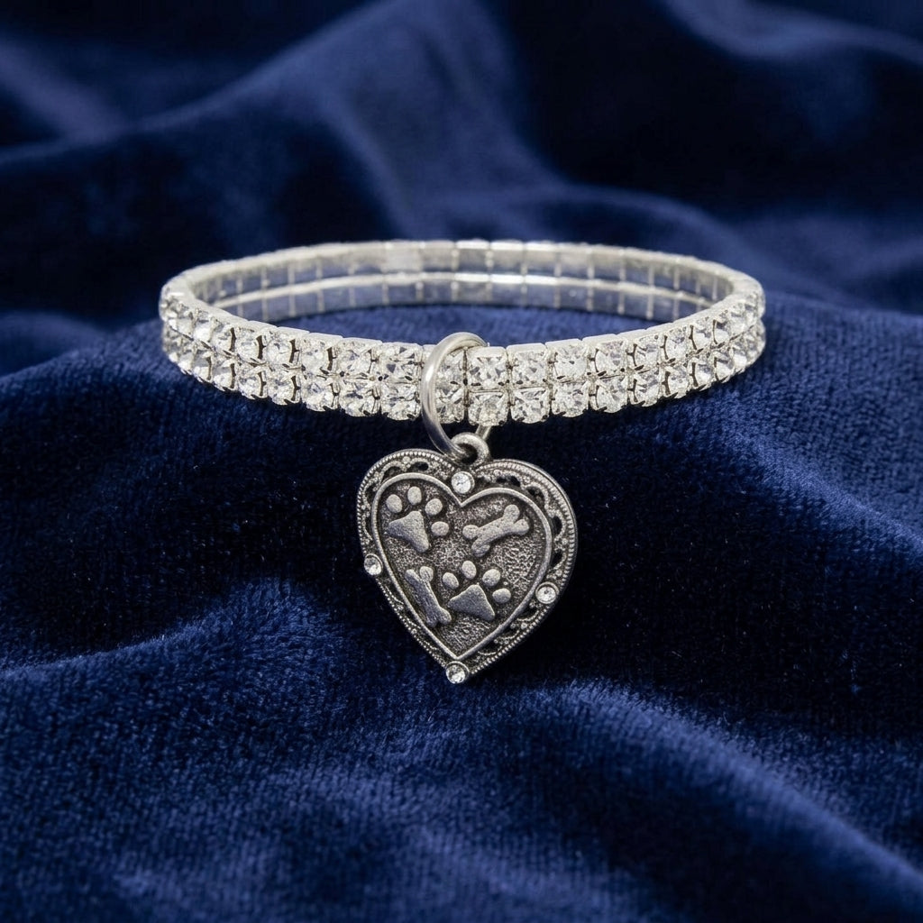 Two Row Rhinestone Crystal Stretch Bracelet With Paws And Bones Heart Charm resting on dark blue fabric