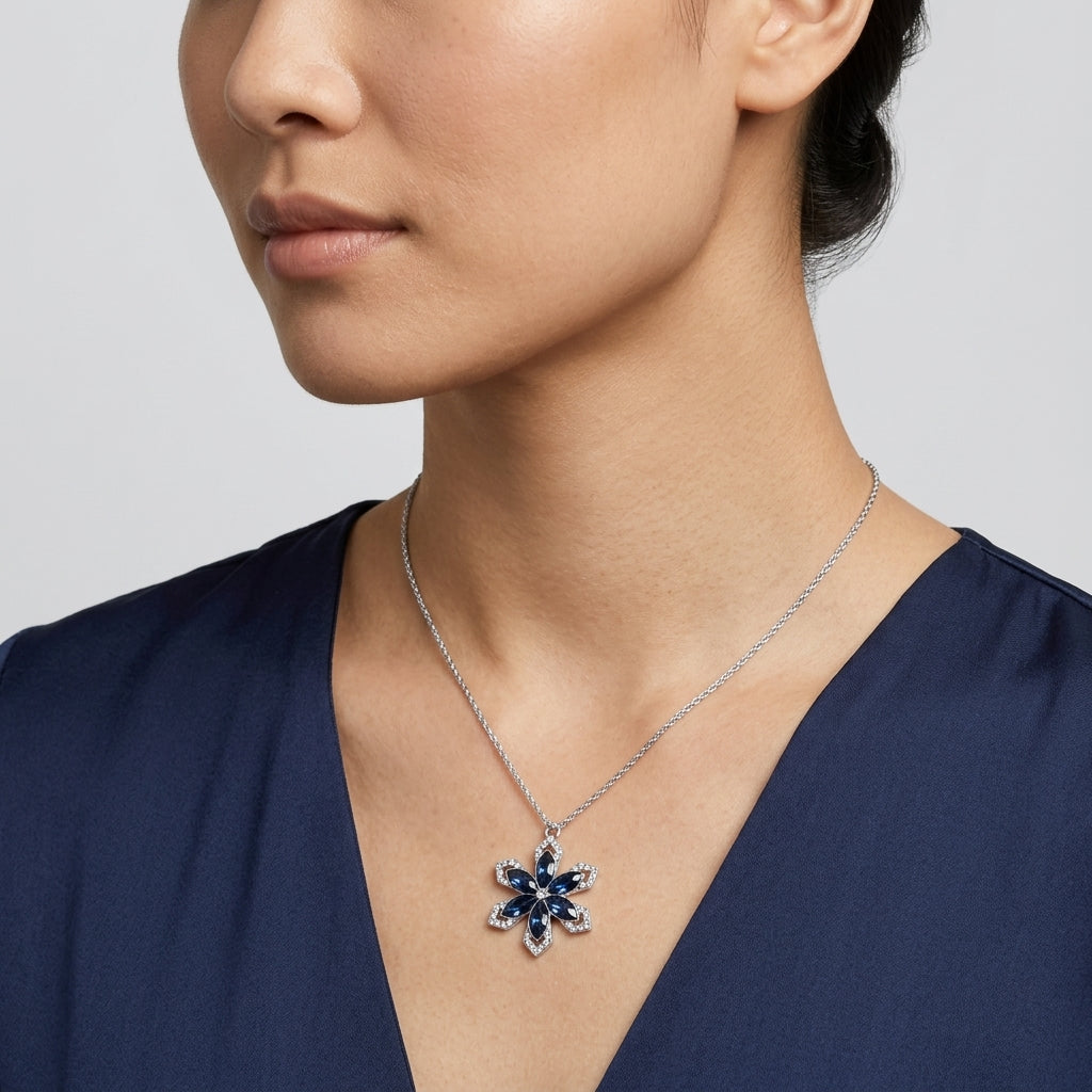 Woman wearing a sapphire blue crystal snowflake pendant necklace that has a silver tone chain