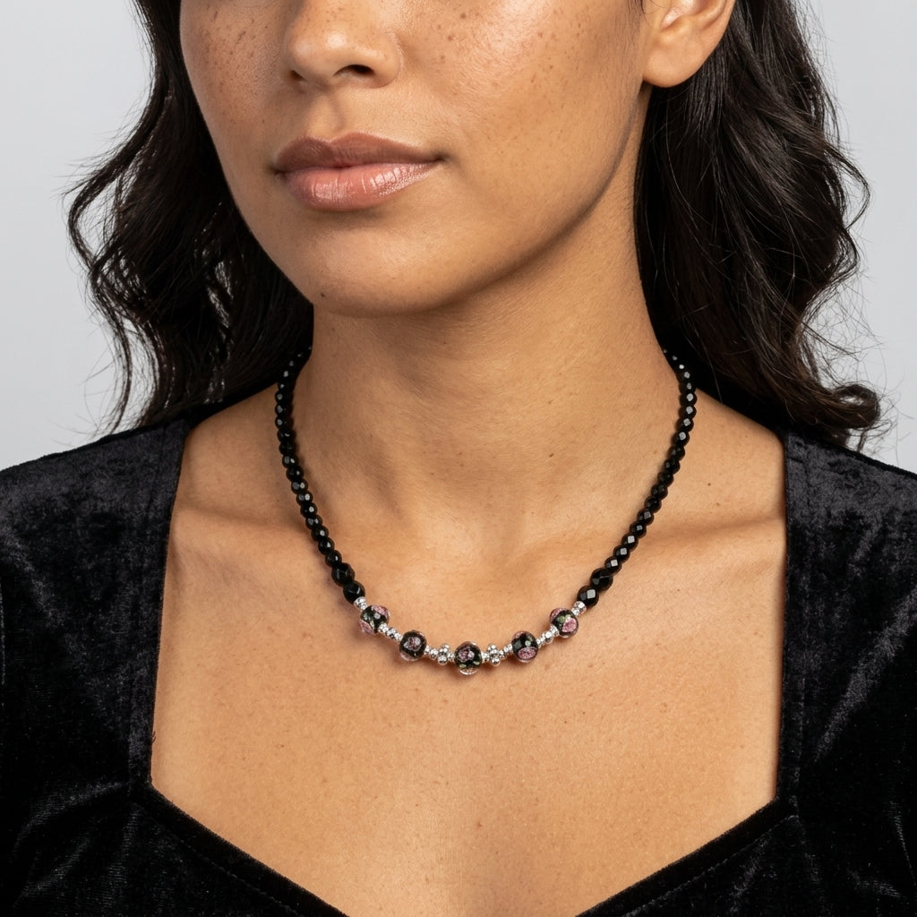Woman in a black dress wearing a black beaded necklace with pink floral motifs