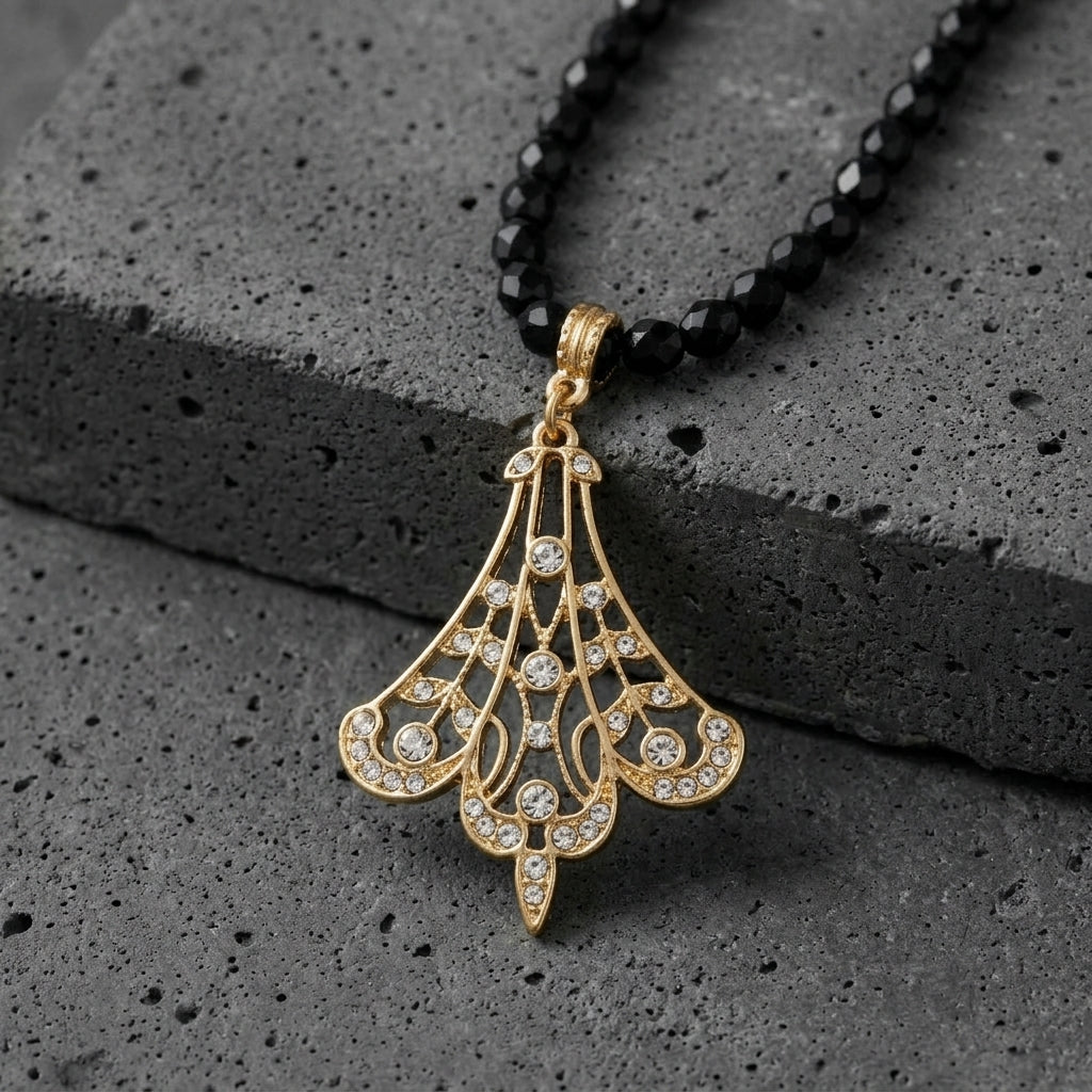 Minuit Black Glass Strand Bead Gold Filigree Fan & Crystals Pendant Necklace resting on dark stone surface