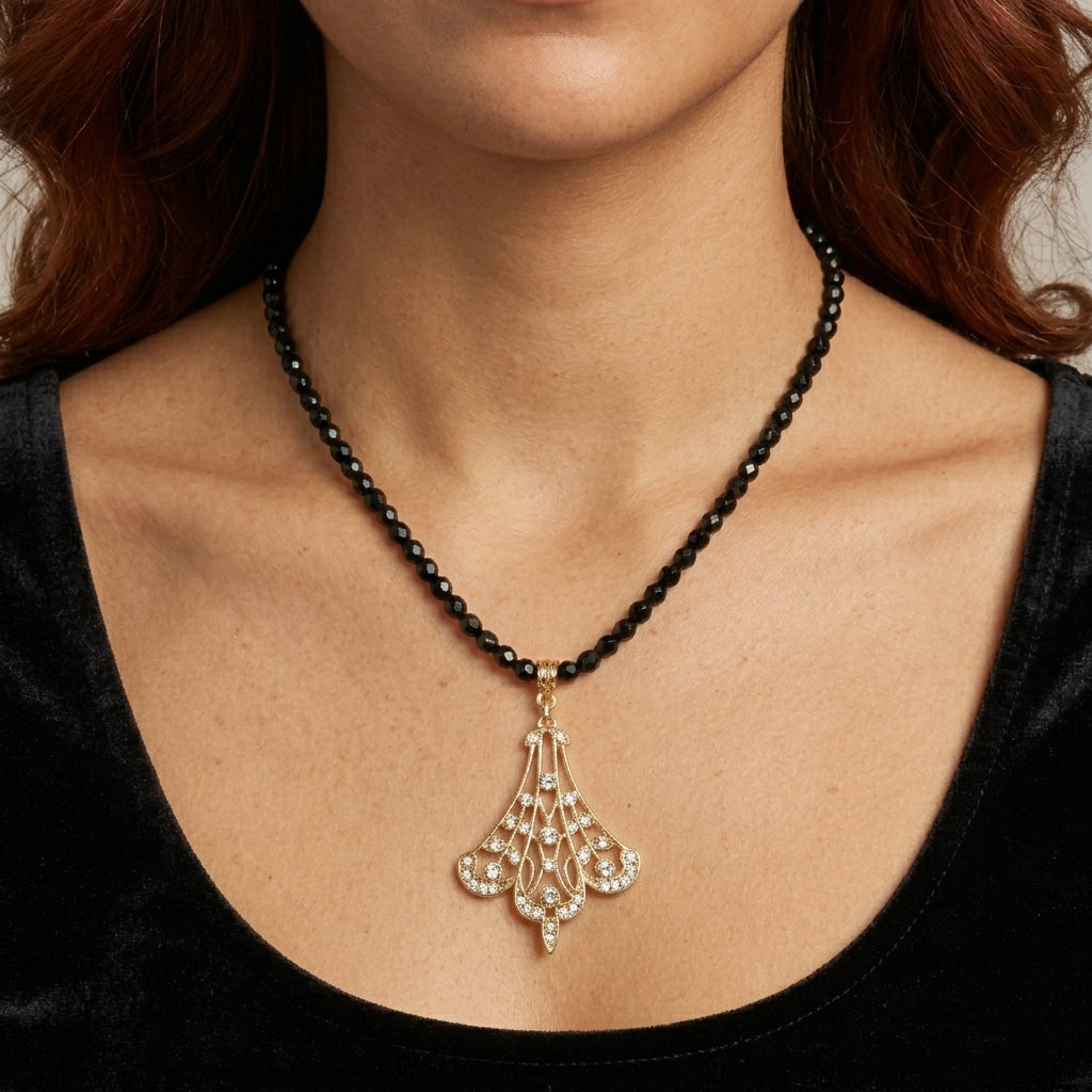Close up of a woman's neckline wearing our Minuit Black Glass Strand Bead Gold Filigree Fan & Crystals Pendant Necklace