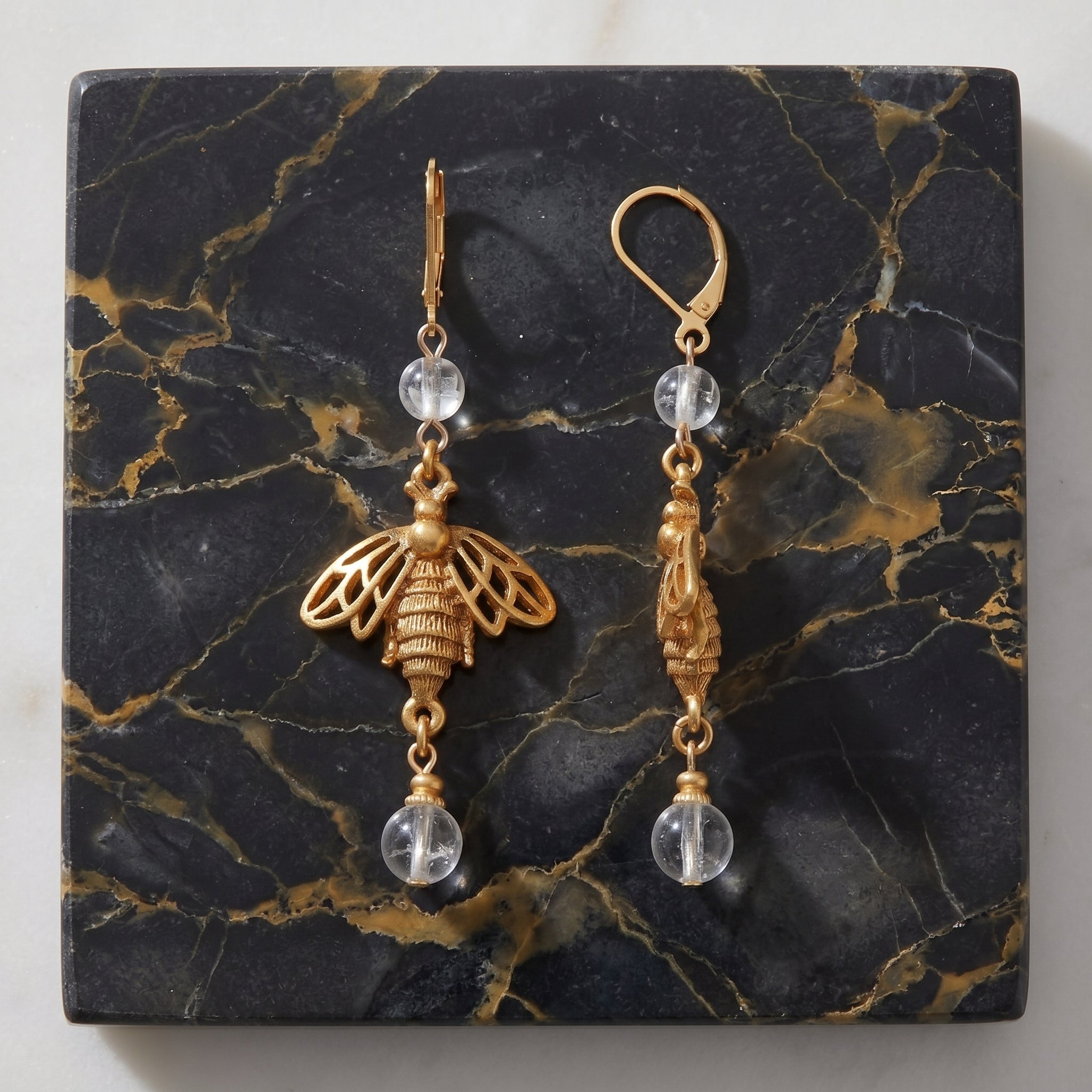 Bee Euro Crystal Dangle Earrings on a gold and black marble stone surface