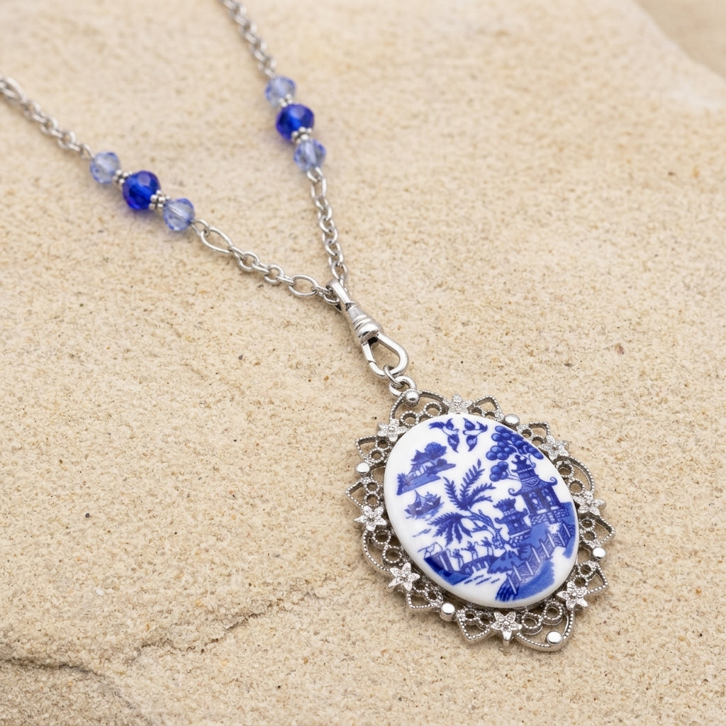 Light Sapphire Crystal Blue Willow Pagoda Oval Swivel Pendant Necklace on beige sandstone surface