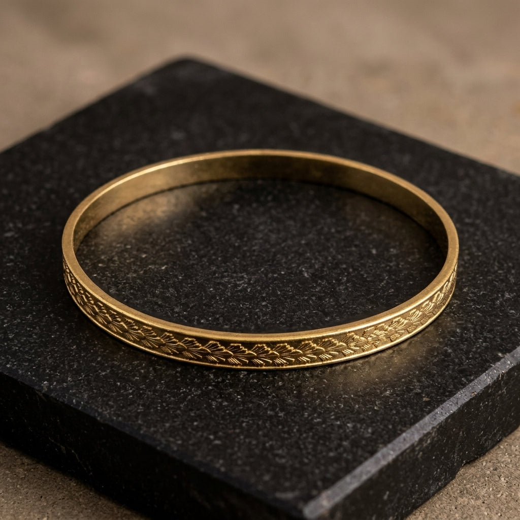 Gold Classic Leaf Bangle Bracelet resting on a slab of dark stone