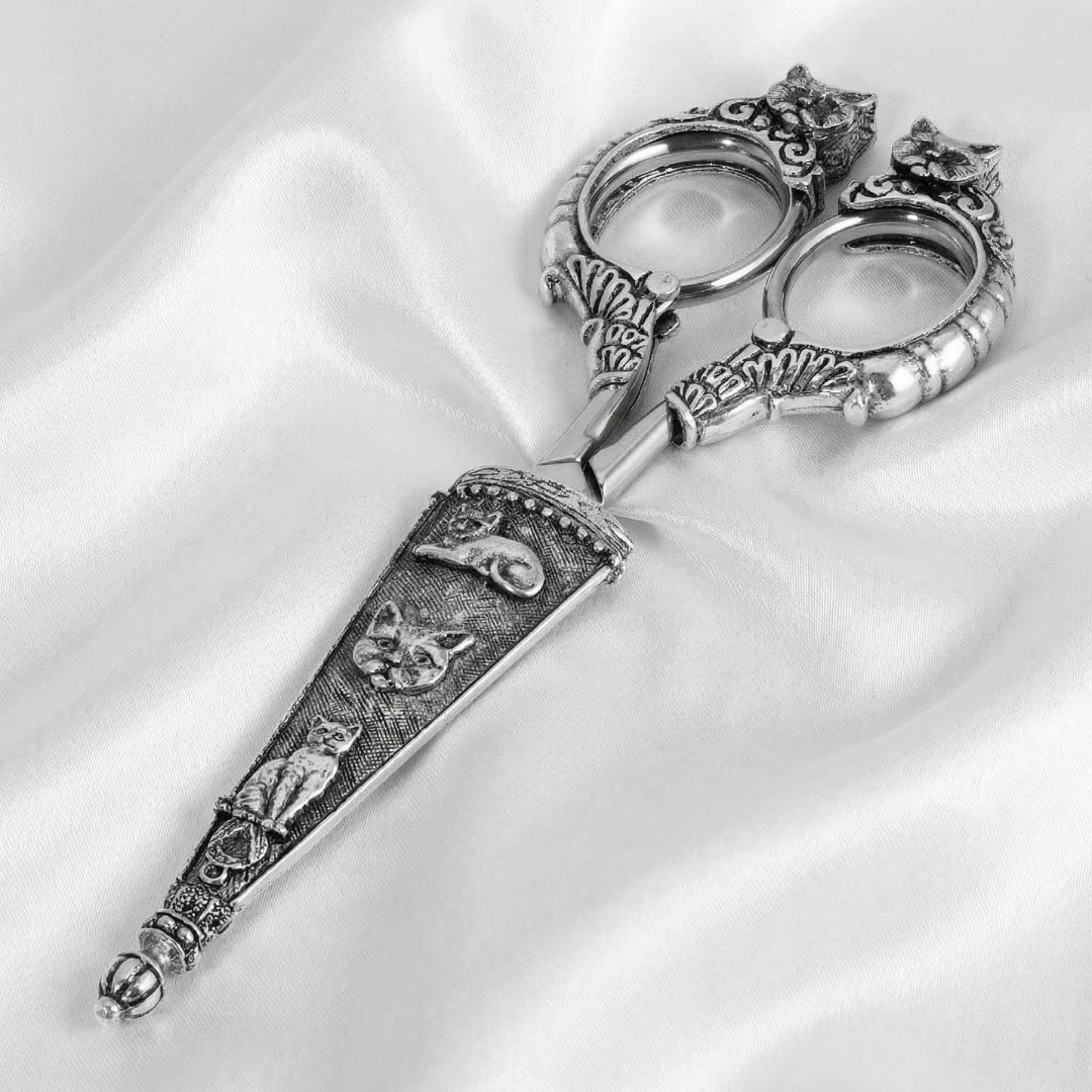Decorative silver cat scissors on a white satin background