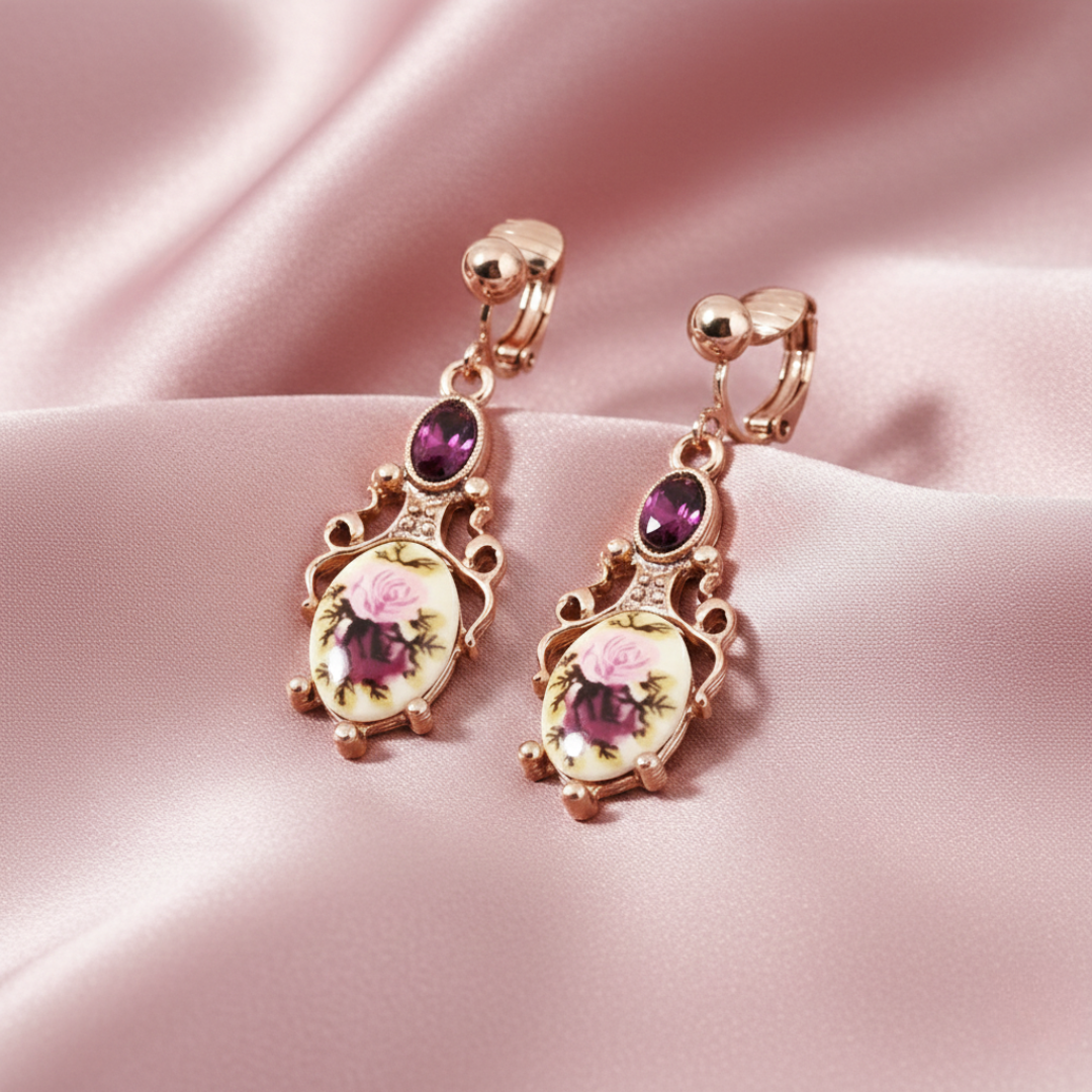 Pair of ornate earrings with floral designs on a pink satin background