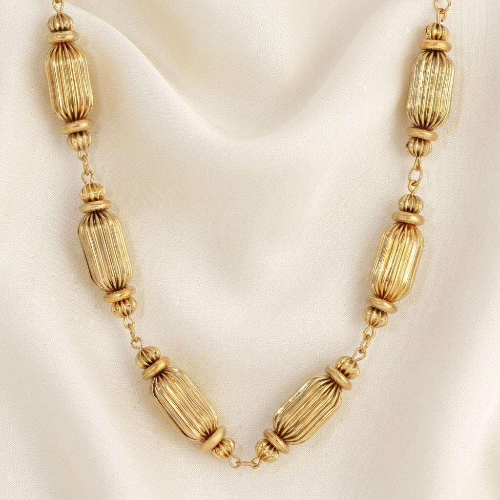 Gold tone multi-beaded necklace resting on a cream satin fabric