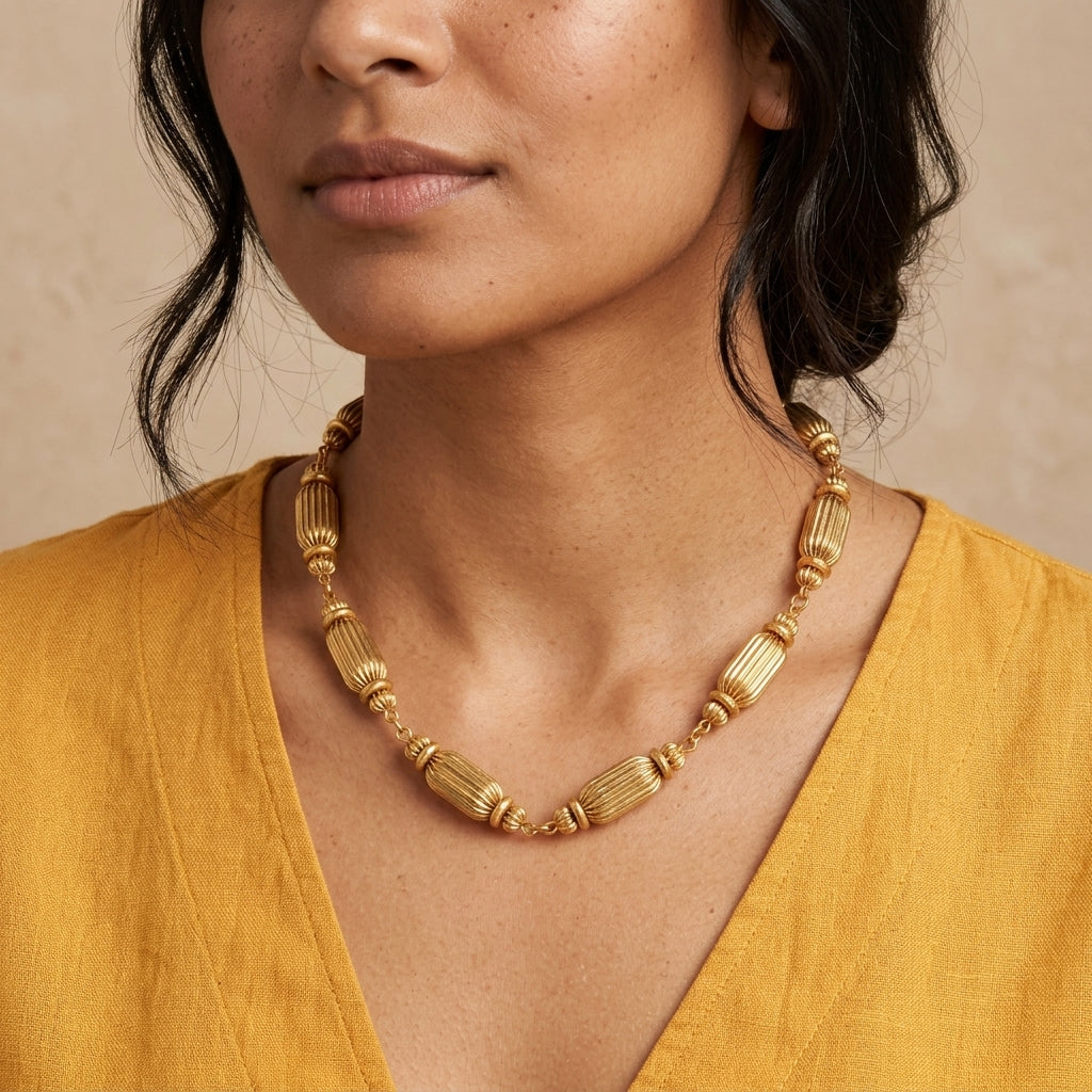 Women in a yellow top wearing a gold tone multi-beaded necklace.