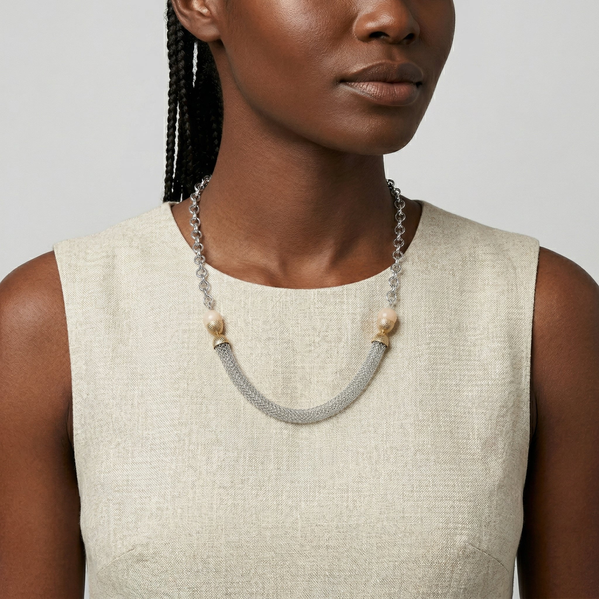 Woman wearing a tube and mesh silver tone chain necklace with beige moonstones