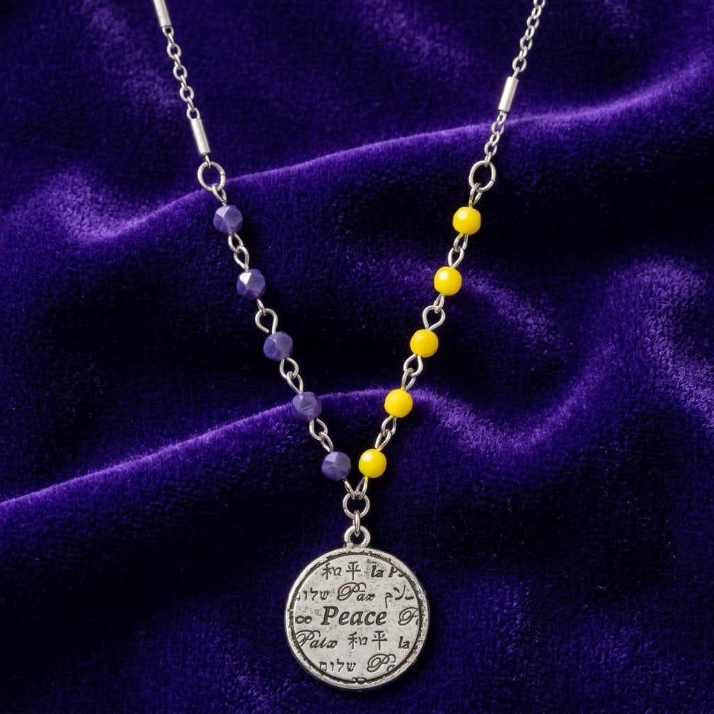Necklace with blue and yellow beads and a peace pendant on a purple velvet background