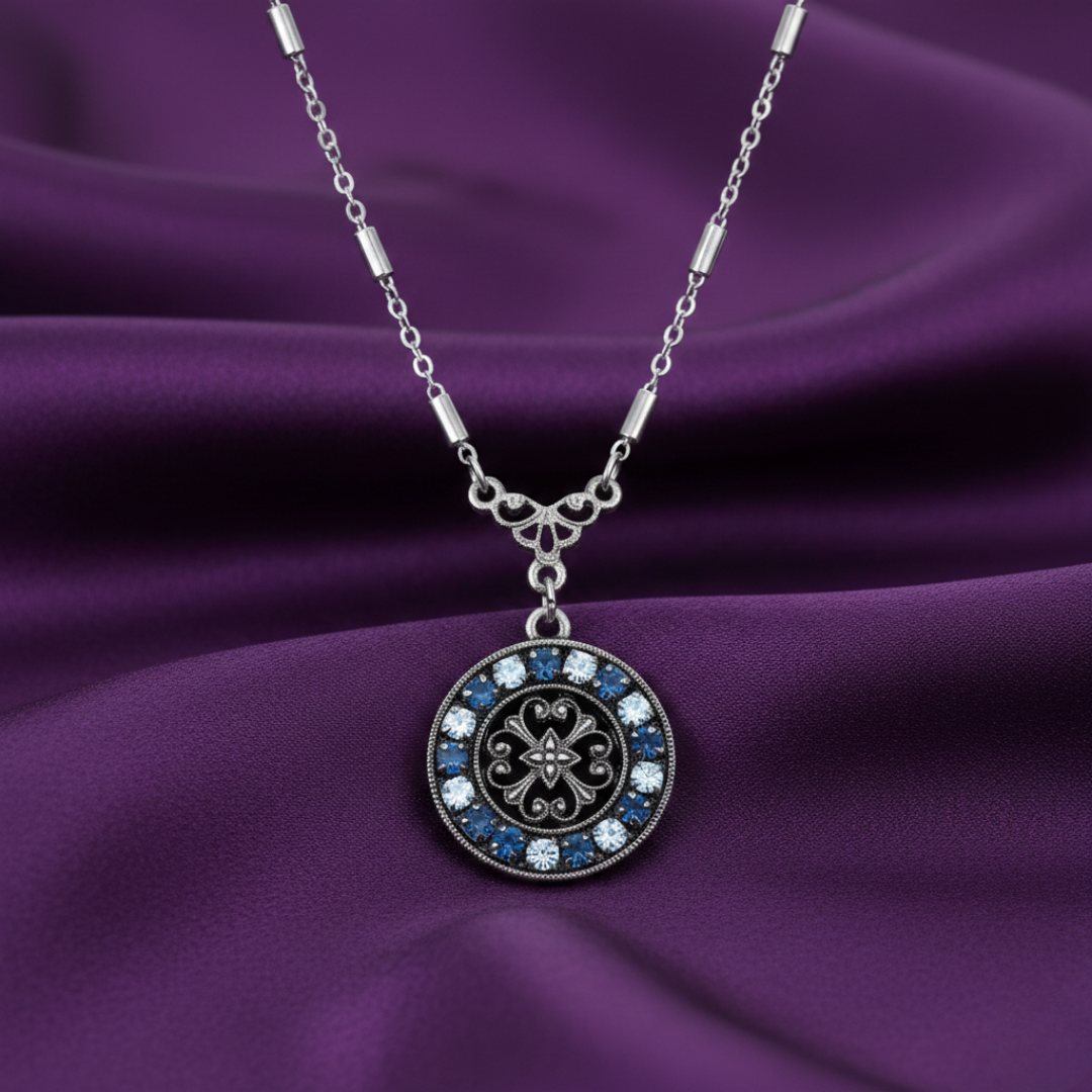 Silver necklace with a decorative pendant full of crystals on a purple fabric background